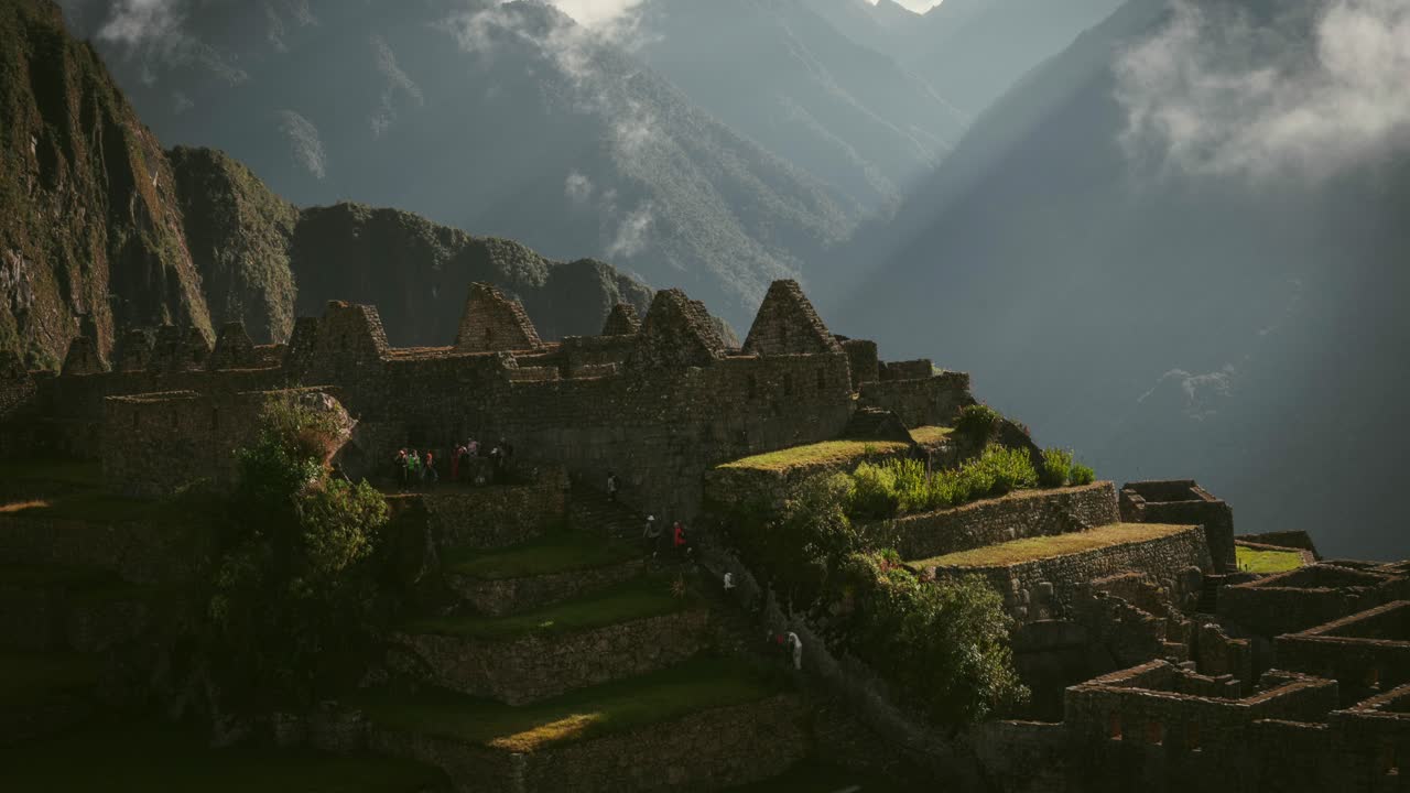 Clouds roll over the ruins of Machu Picchu, Peru, in a mesmerizing time lapse at sunrise with visitors ascending stairs in tour group