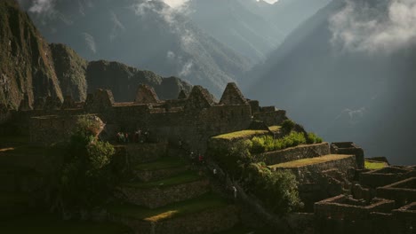 clouds roll over the ruins of machu picchu, peru, in a mesmerizing time lapse at sunrise with visitors ascending stairs in tour group