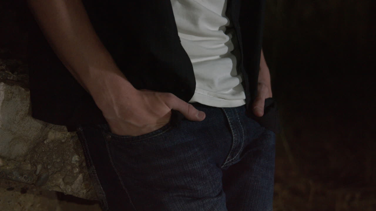 A man places his hands in his jean pockets.