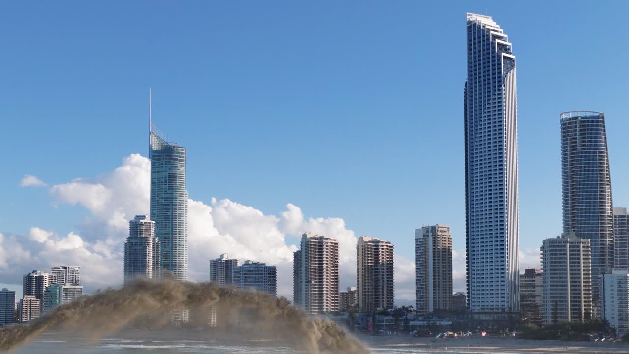 Aerial view of sand dredging near skyscrapers on Gold Coast, Australia. Clear skies and urban skyline create a dynamic coastal scene