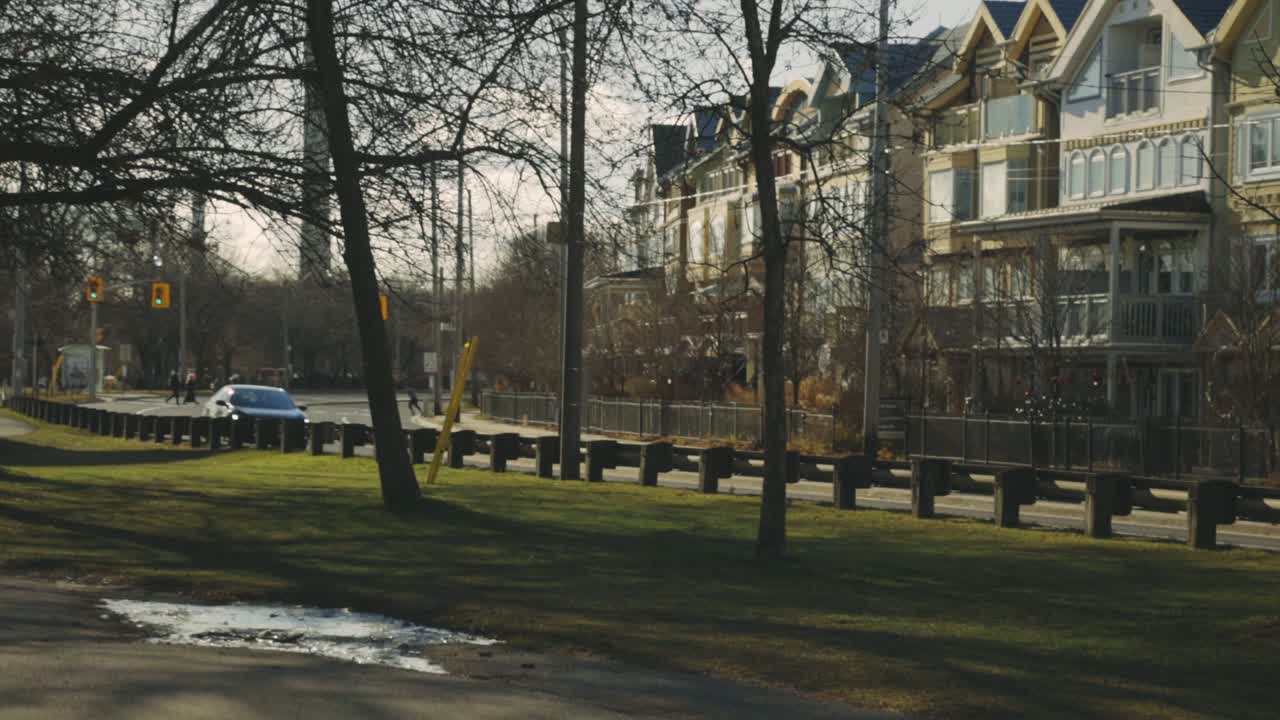 conducción de automóviles en una carretera asfaltada con árboles desnudos y una hermosa mansión en una mañana soleada en la temporada de otoño - plano amplio