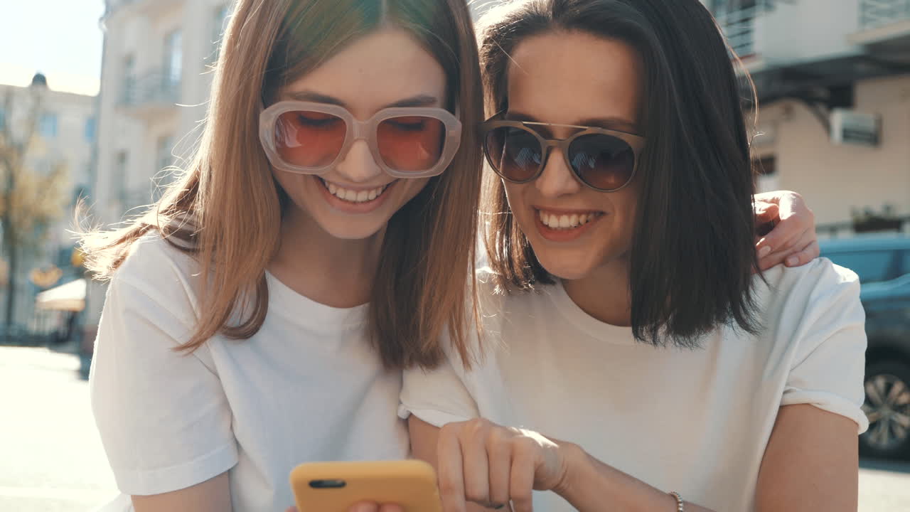 dos amigos compartiendo un teléfono inteligente en la ciudad