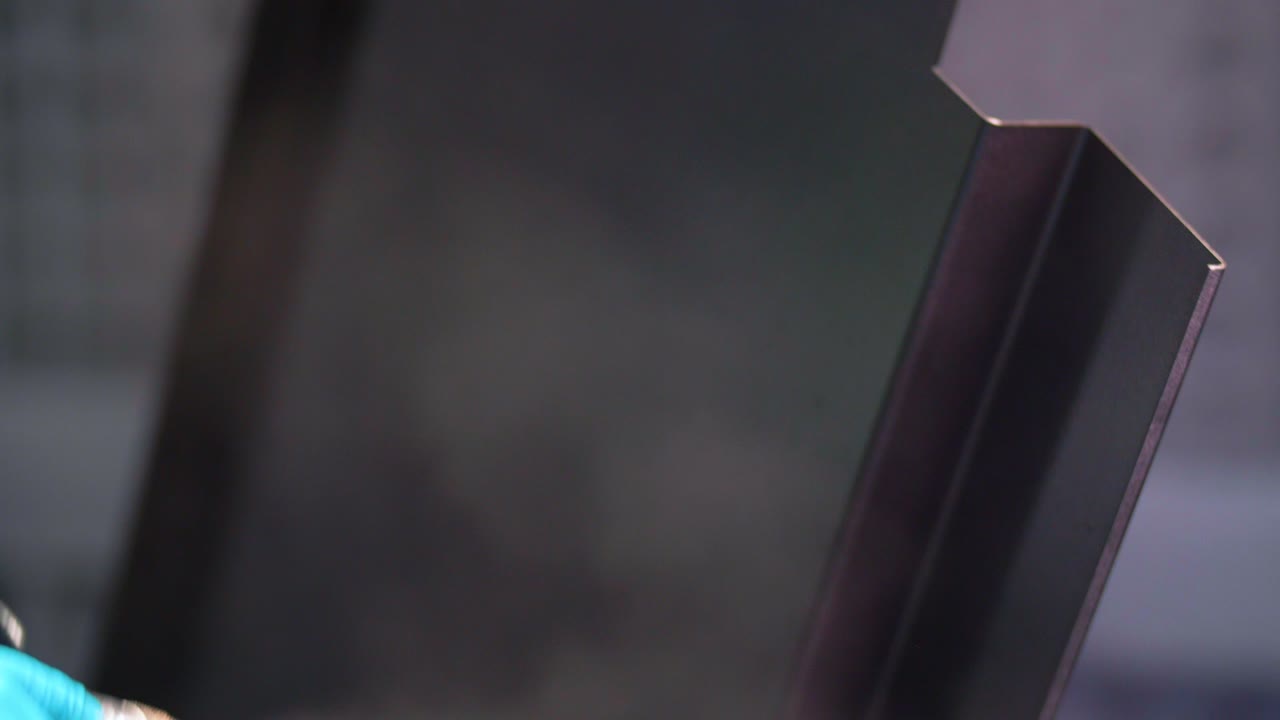 hombre que aplica un recubrimiento en polvo anticorrosión negro a una chapa metálica utilizando una pistola pulverizadora en la fábrica