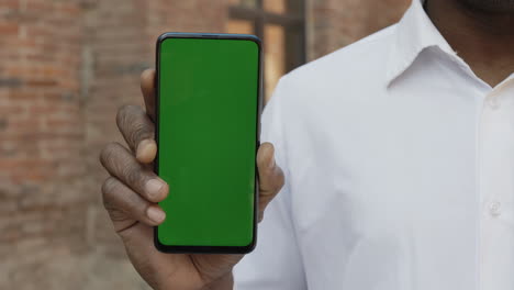 person holding a smartphone with a green screen