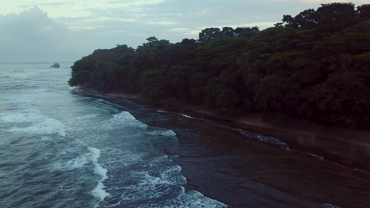 воздушный снимок, летящий над бурным карибским морем, открывающий лес и океан в сумерках в пуэрто-вьехо-де-таламанка в коста-рике