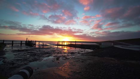 peaceful sunrise, wide angle view over river delta leading to sea and wet beach in texel, the netherlands