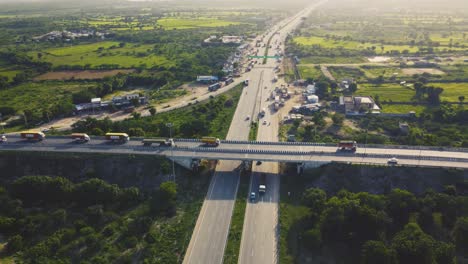 vista aérea de drones de la carretera de cruce de varios niveles de la autopista con camiones en movimiento al atardecer