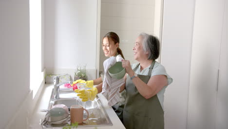 washing dishes together, asian grandmother and granddaughter bonding in kitchen at home