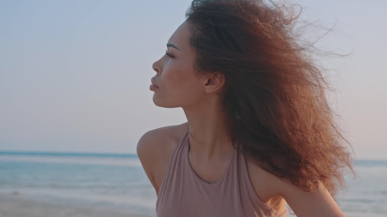 Woman meditating at the beach at sunset