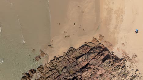 Top-View-Of-Rocky-Shoreline-With-Crystal-Clear-Water-On-A-Sunny-Day