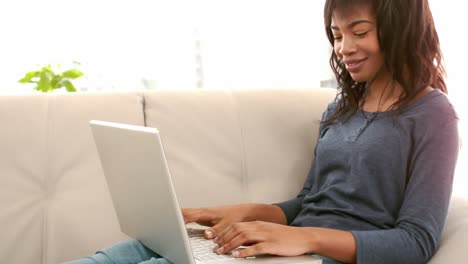 mujer usando su computadora portátil en el sofá
