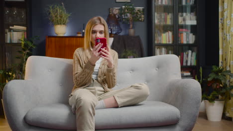 young woman using smartphone while sitting on a couch at home