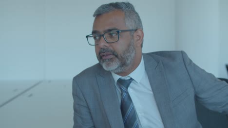 serious pensive grey haired businessman sitting in office space