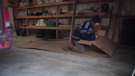 a man is removing staple wires from cardboard to prepare it for use as mulch in gardening - static shot