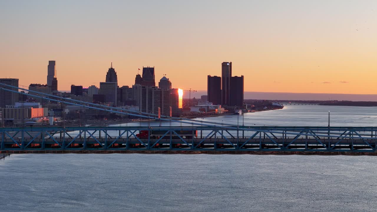 Detroit skyline and cargo truck driving over Ambassador bridge, aerial view during sunset