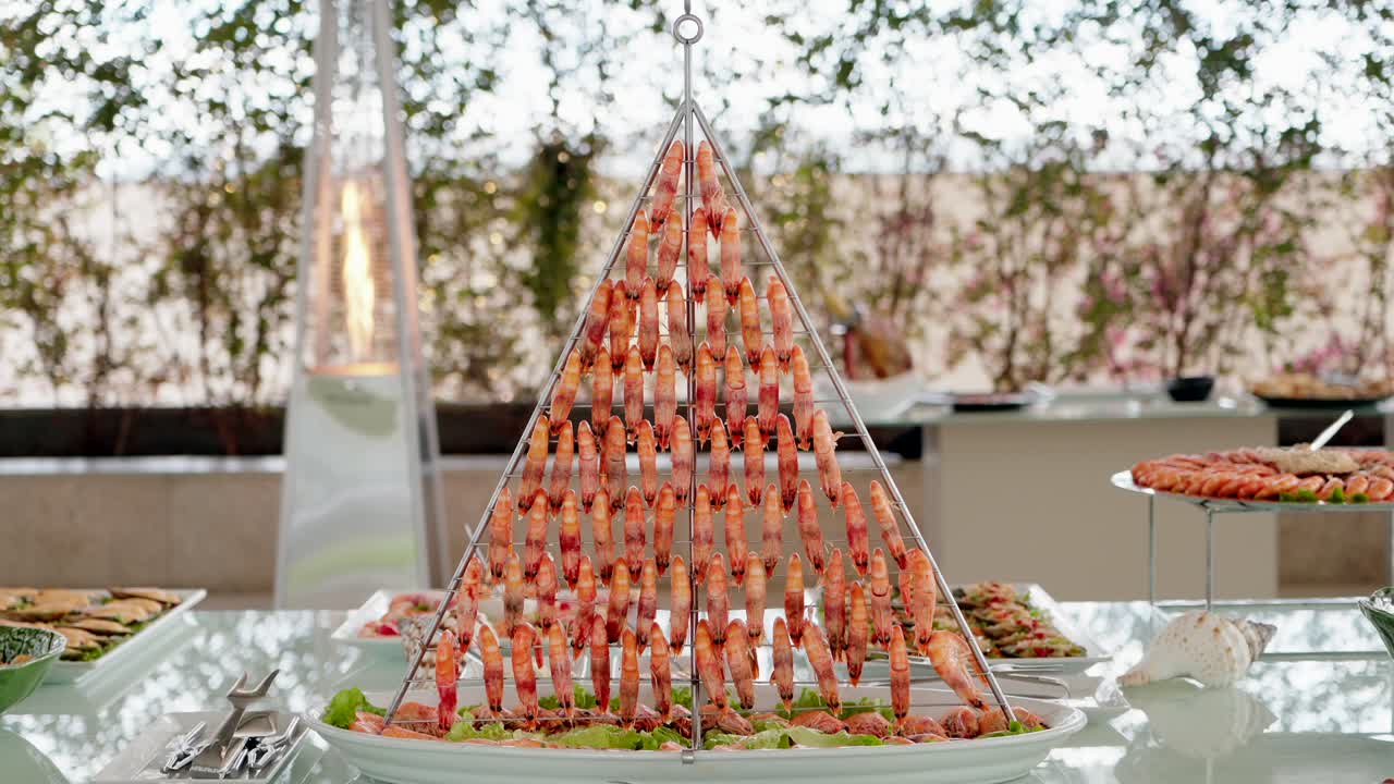 Cooked shrimp arranged in pyramid stand on buffet table for catering event