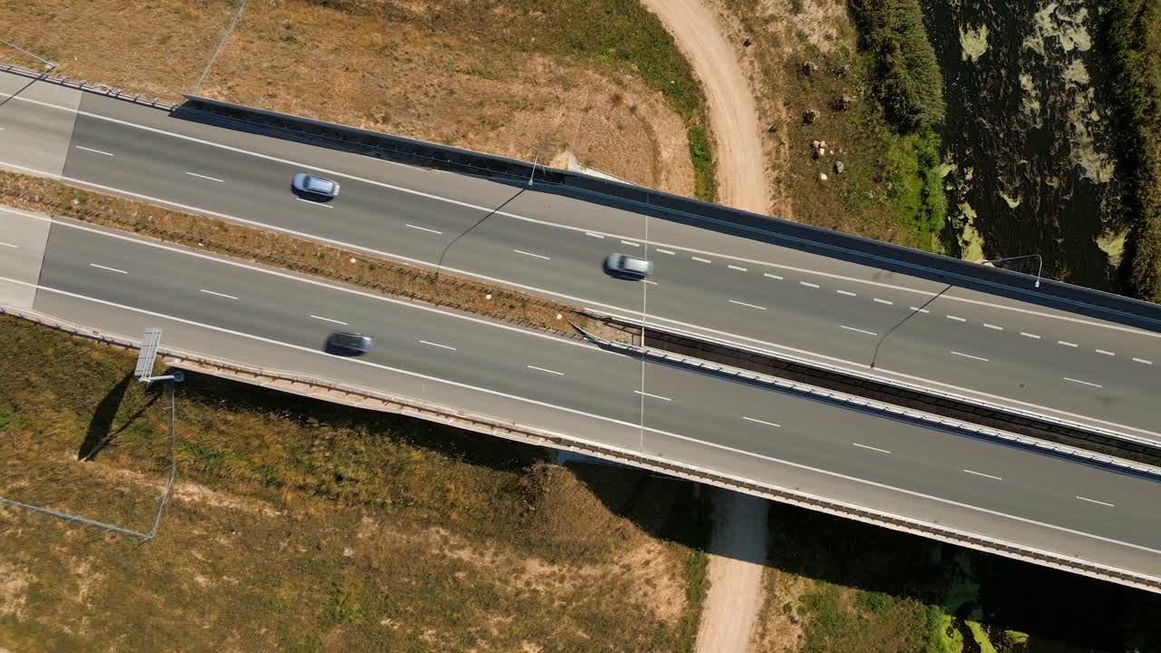 Trucks and cars driving on river bridge road expressway highway through rural landscape, Overhead aerial view