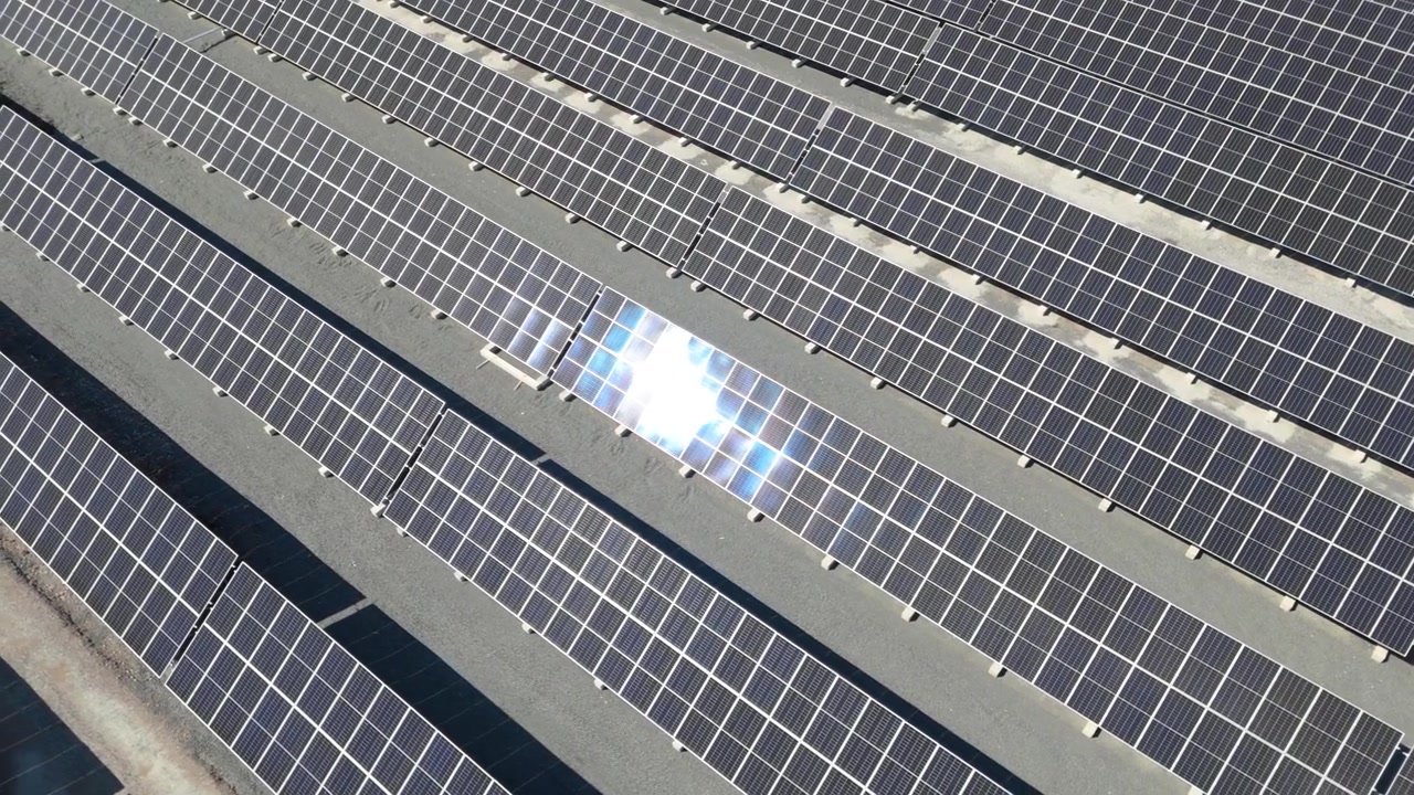 Panoramica aerea che mostra pannelli solari bifacciali in un parco solare in Finlandia, energia rinnovabile, la luce del sole luccica e brilla, ghiaia tra le file