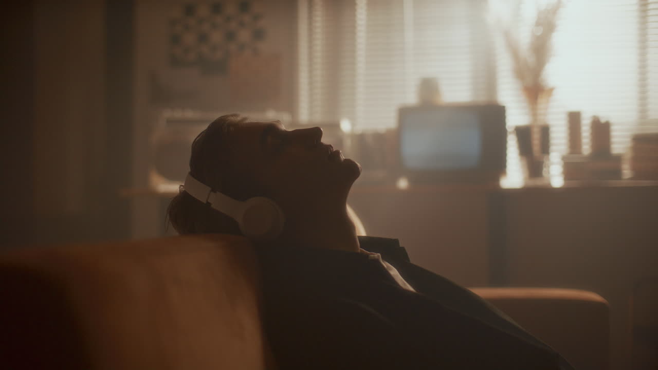 Relaxed Man in Headphones Chilling on Couch in Retro-Style Room