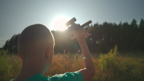 young boy flying an airplane in the country