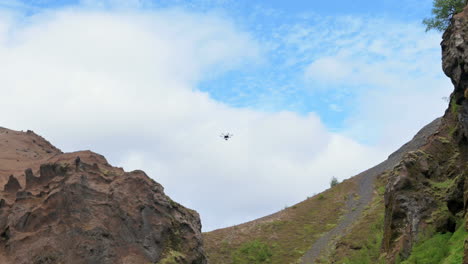 big drone flying above rocky cliffs of a narrow ravine