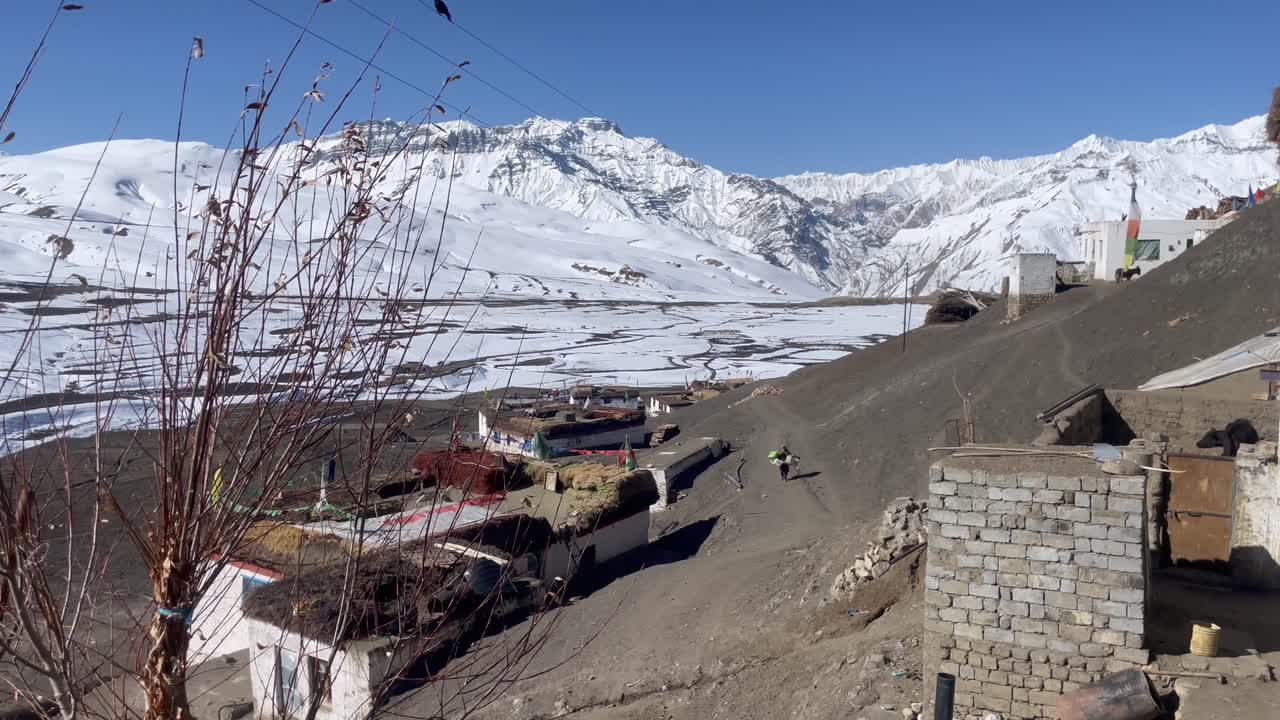 인도 히마찰 프라데시 의 스피티 계곡 의  ⁇ 은 날 에 마을 의 황량 한 언덕 에서 짐 을  ⁇ 고 있는 여자