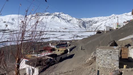 Eine-Frau-Mit-Last,-Die-An-Einem-Sonnigen-Tag-Im-Spiti-Tal-In-Himachal-Pradesh,-Indien,-Auf-Einem-Kargen-Hügel-In-Einem-Dorf-Spaziert