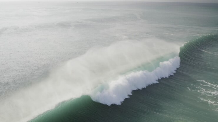 surfer catching a huge wave in Uluwatu ocean bali island indonesia travel destination aerial footage
