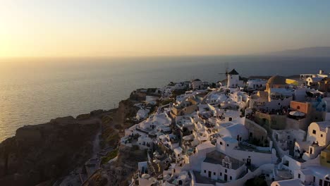 Toma-Panorámica-Suave-Sobre-Oia-Construida-Sobre-Un-Acantilado-Durante-La-Puesta-De-Sol,-Isla-De-Santorini,-Cícladas,-Grecia