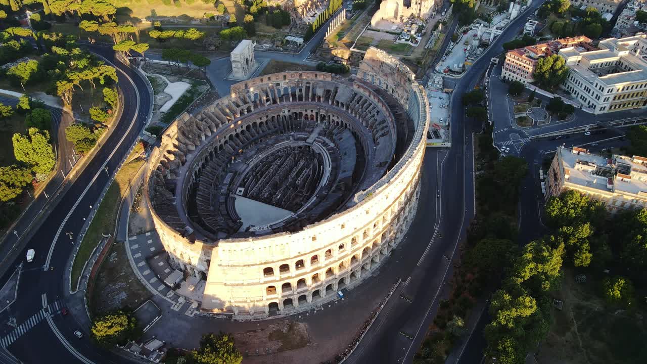 Aerial morning view of ancient Colosseum, soft light, long shadows, calm roads