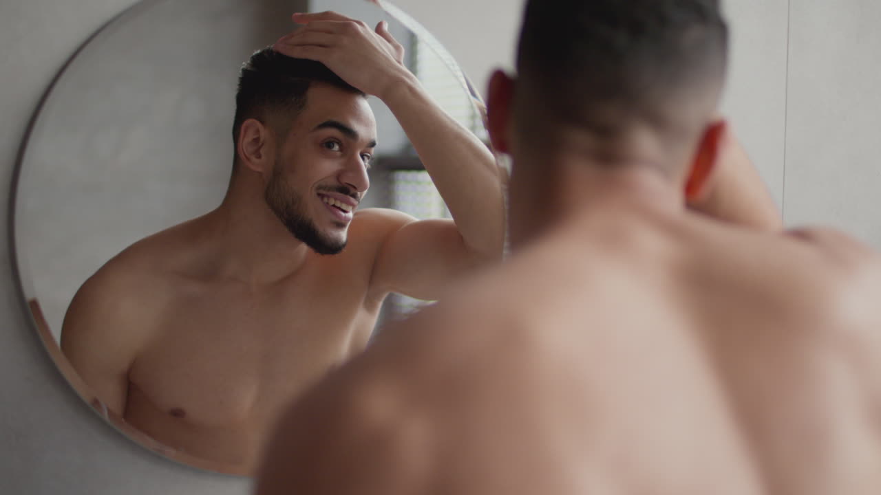 Man Styling Hair in Bathroom Mirror
