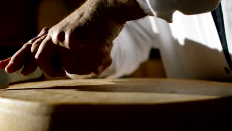 in a cheese industry, a master cheese maker mixes the milk and the curd to make a form of parmesan:the cheese maker does it according to the old italian tradition.