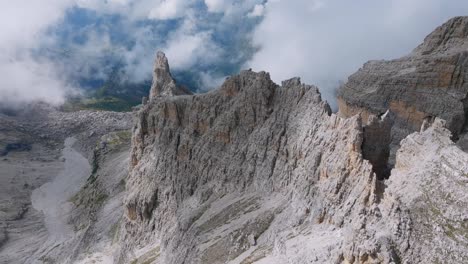 Aerial-tilt-down-flight-over-rock-formation-with-summit-and-valley-view-during-sunny-day