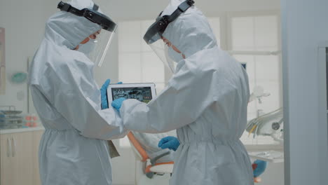 team of dentists wearing ppe suits while looking at x ray