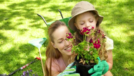 Cute-little-girl-holding-pot-of-flowers-with-her-mother