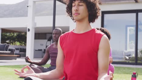 happy group of diverse friends doing yoga in garden, meditating