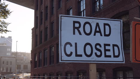 white road closed sign under bridge, streets of new york city, close up