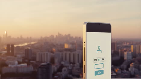 smartphone with 2fa login screen overlooking a city at sunset