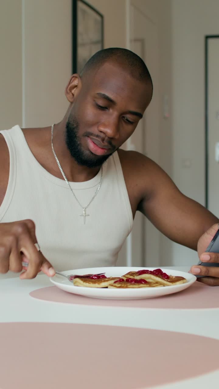 hombre comiendo panqueques y usando el teléfono