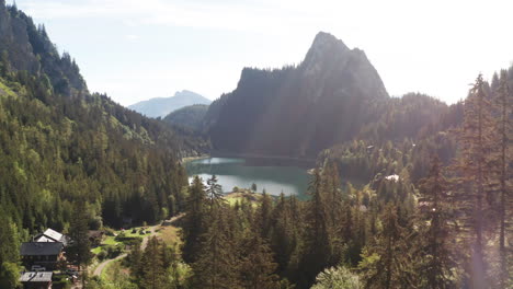 Flying-low-over-treetops-towards-stunning-lake-and-beautiful-mountainside