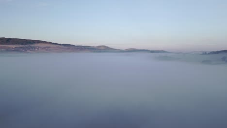 Escena-Tranquila-De-Colinas-Que-Emergen-Sobre-Una-Vasta-Extensión-De-Niebla-Bajo-Un-Cielo-Que-Pasa-De-La-Noche-Al-Amanecer