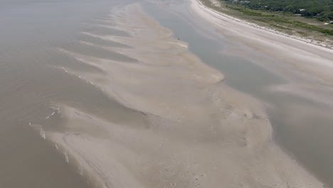 subtle, fading lines of submerged sand reveal the transition from land to sea in a minimalist, painterly meeting of elements