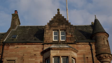 red stone house with roof and windows on sunny day in town