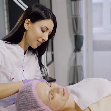 a cosmetologist makes injections for a woman in a beauty center. the client is laying on the couch during the procedure. mesotherapy.