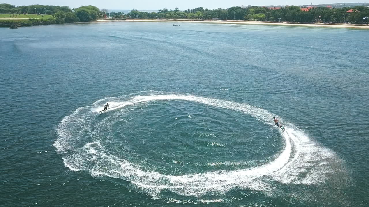 два джетсерфингиста выполняют трюки у океанского острова, съемка с воздуха