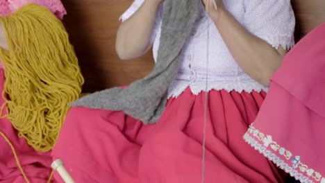 basket of thread coils and woman knitting with them