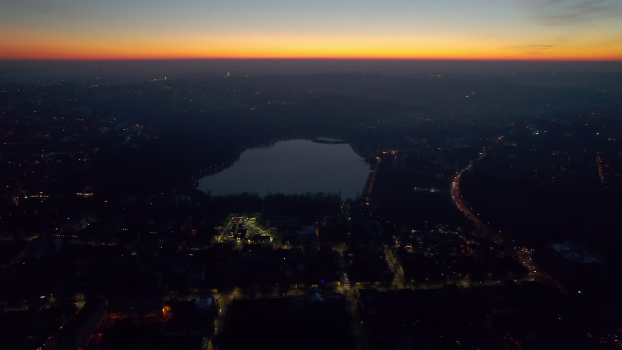 Aerial drone view of Chisinau at sunset, Moldova. View of city centre with lake, buildings, roads, illumination