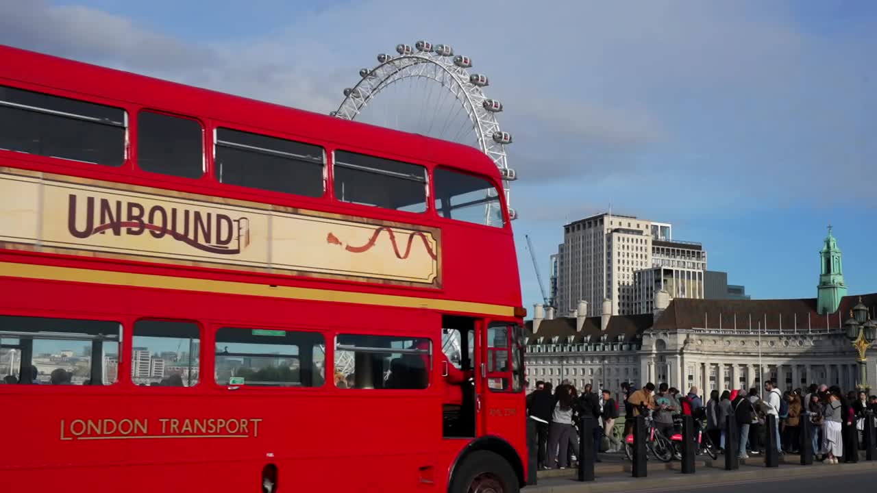 Tourists and iconic red double-decker bus on Westminster Bridge with the London Eye in background