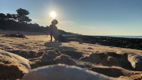 Close-up-of-guy-practicing-yoga-on-a-beach-under-sunshine