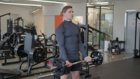 Handsome-Athletic-Man-Does-Bicep-Barbell-Curls-with-a-Heavy-Weight-in-Empty-Gym